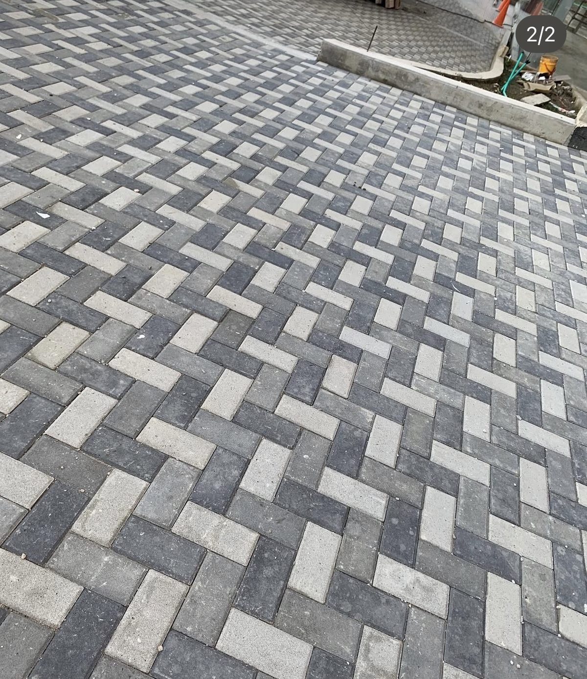 Vía urbana pavimentada con adoquines de concreto en patrón espiga bicolor